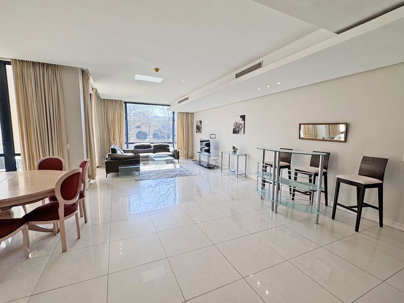 Spacious open-plan living and dining area featuring polished tiled flooring, recessed ceiling lighting, ducted air conditioning, and large windows providing ample natural light.