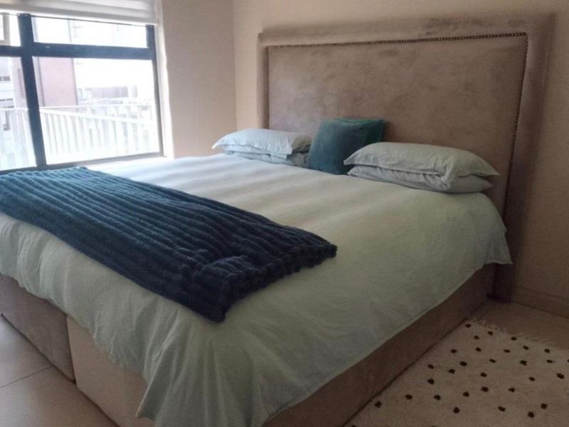 A well-lit bedroom featuring large windows and neutral tiled flooring, providing a comfortable and functional living space.