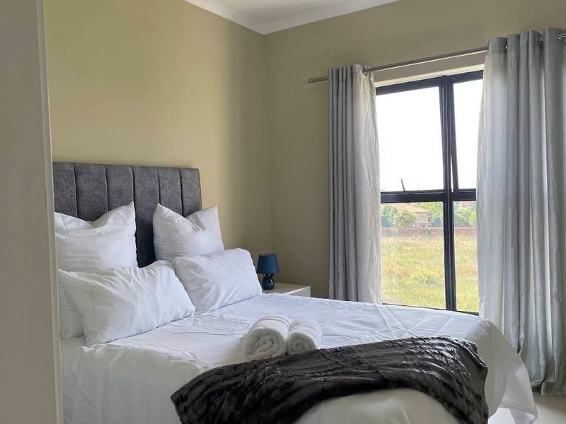 A well-maintained bedroom featuring neutral wall tones, a large aluminium-framed window, and coving detail, offering a clean and comfortable living space.