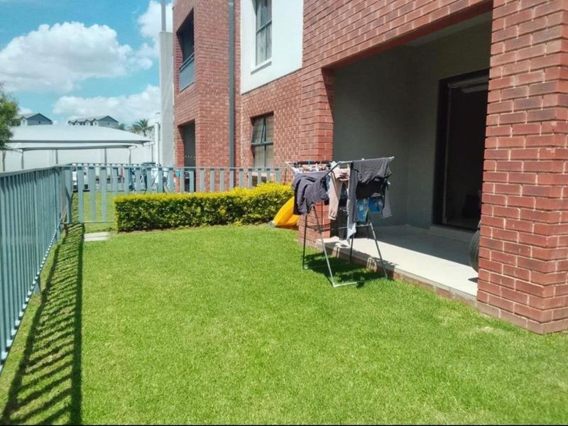 A private rear garden area featuring a well-maintained lawn, a covered patio space, and brick exterior wall finishes.