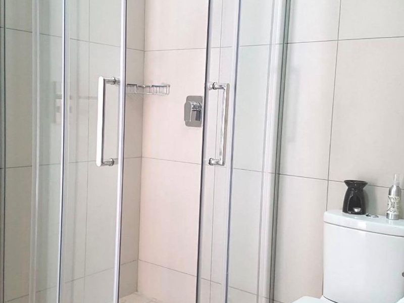 A clean, modern bathroom featuring a glass-enclosed shower with tiled walls and a standard white toilet.
