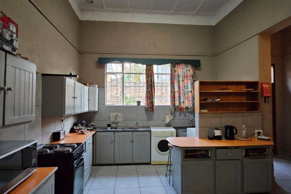 A dated kitchen featuring built-in cabinetry, tiled flooring, and a functional layout with space for laundry appliances.