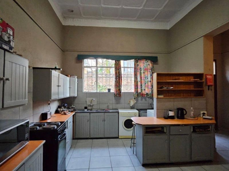 A dated kitchen featuring built-in cabinetry, tiled flooring, and a functional layout with space for laundry appliances.