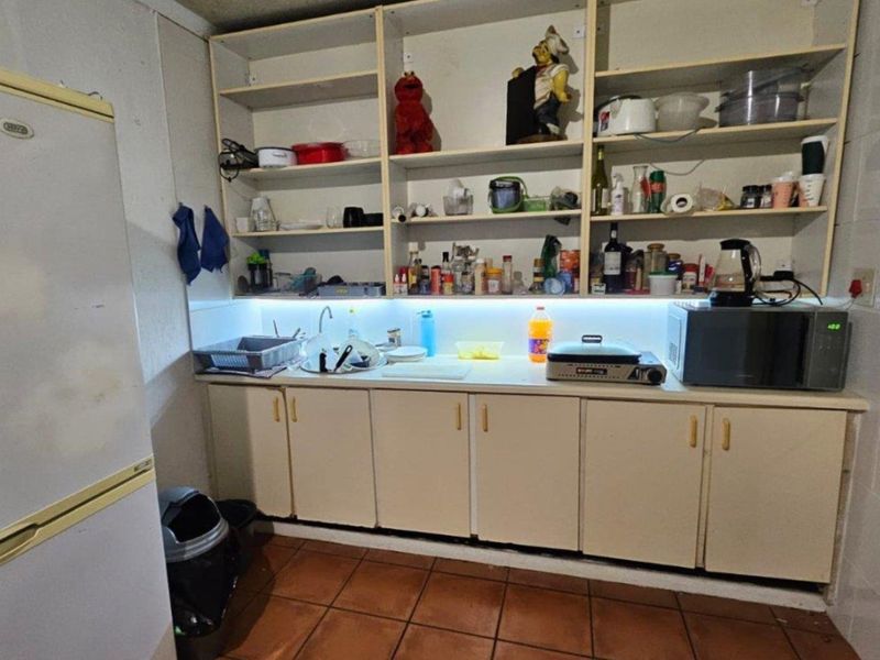 A functional scullery area featuring built-in cabinetry, open shelving, tiled splashbacks, and under-cabinet lighting, providing practical storage and prep space.
