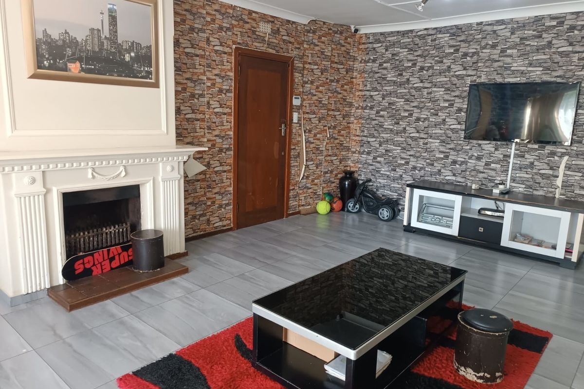Living room featuring a traditional fireplace with mantelpiece, tiled flooring, and textured feature walls.