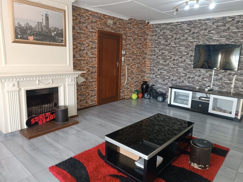 Living room featuring a traditional fireplace with mantelpiece, tiled flooring, and textured feature walls.