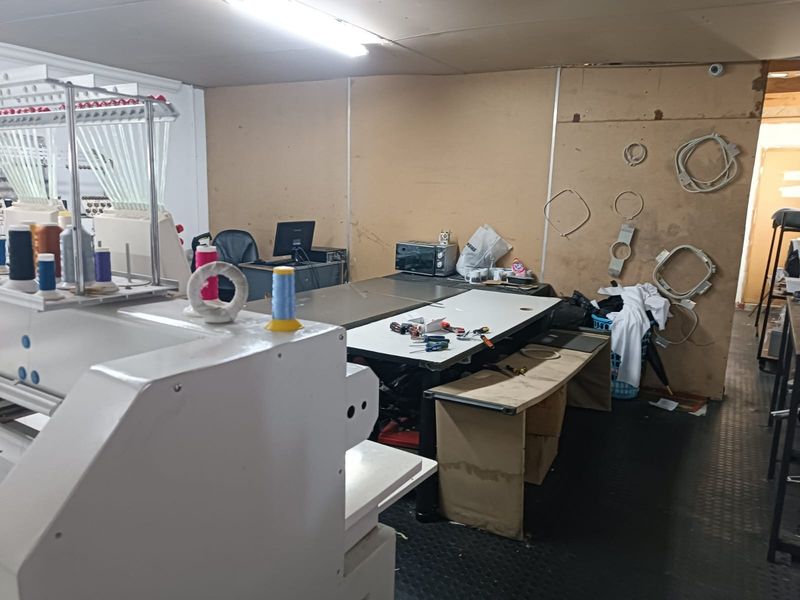 A utility or workshop space featuring industrial rubber flooring and basic wall paneling, currently utilized for commercial equipment and storage.