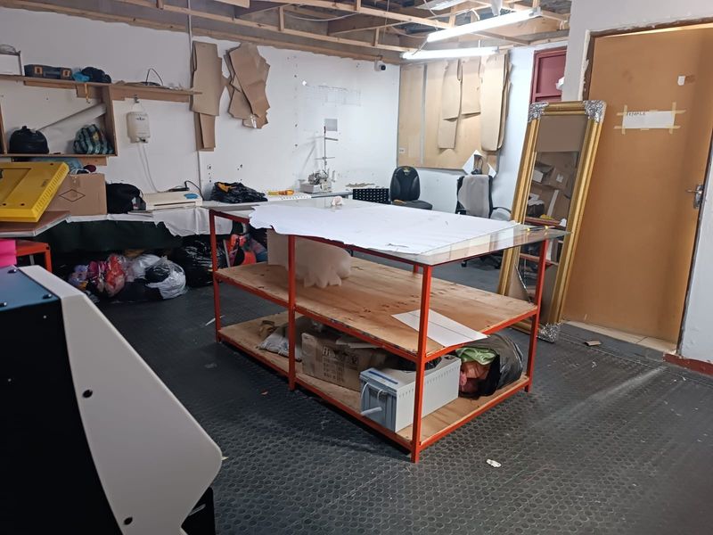 A functional utility or workshop space featuring exposed ceiling joists, durable rubber flooring, and a solid core door, suitable for various commercial or hobby uses.