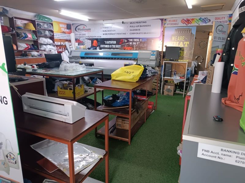 A commercial utility space currently utilized as a printing workshop with industrial equipment and signage.
