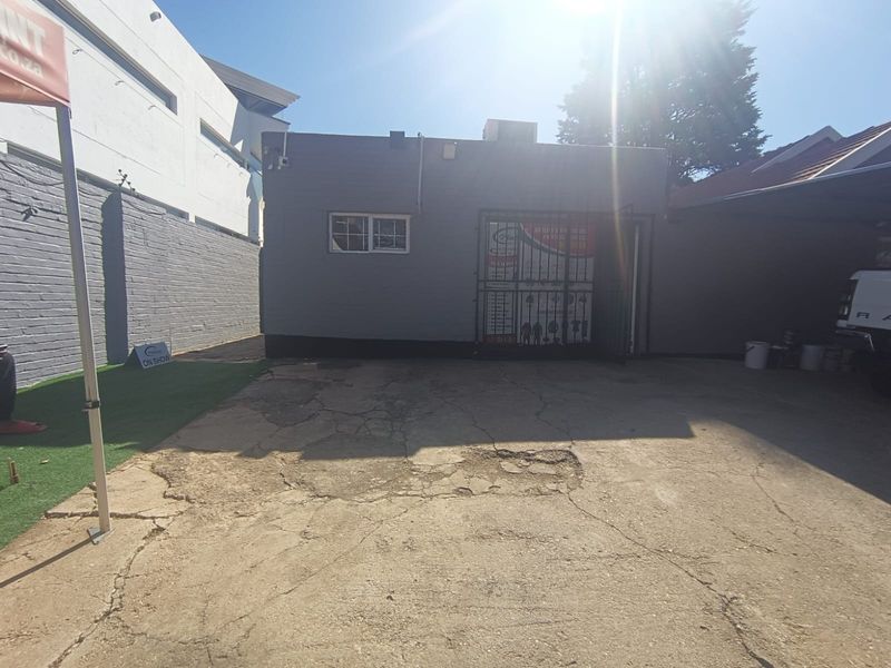 Front exterior view of the property featuring a concrete driveway with visible surface cracking and a secure gated entrance.