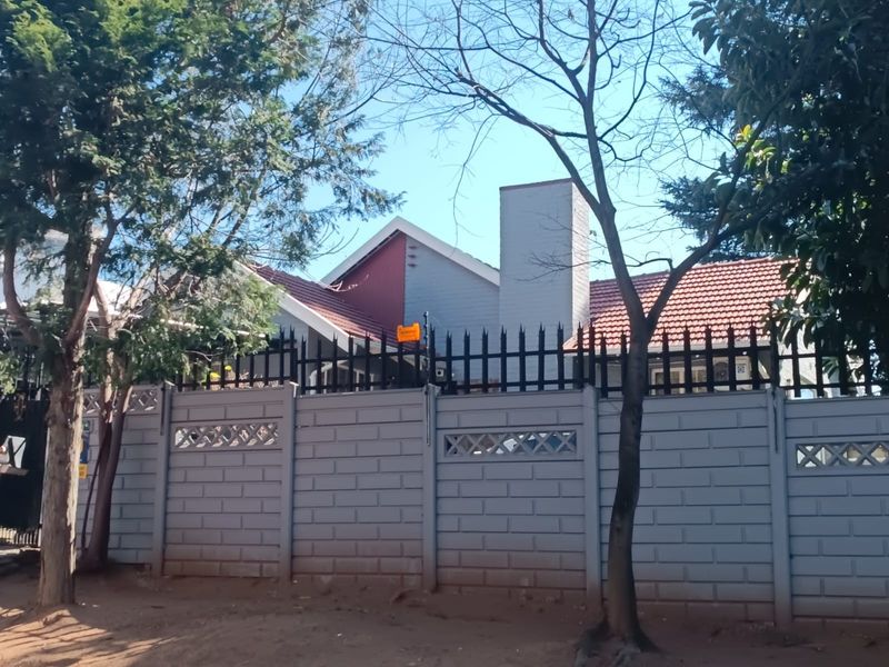 Front view of the property featuring a secure precast concrete boundary wall with steel fencing and a tiled roof structure.