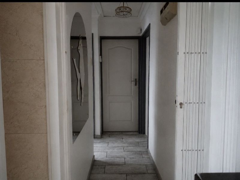 A functional hallway featuring tiled flooring, an arched wall detail, and a security gate, providing access to other areas of the home.