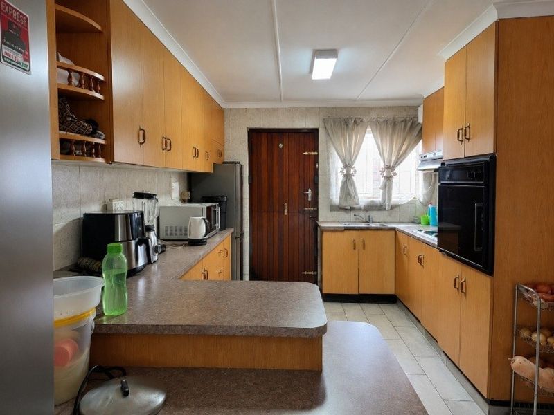A functional kitchen featuring wood-look laminate cabinetry, built-in oven, extractor fan, and ample countertop space with a practical layout.