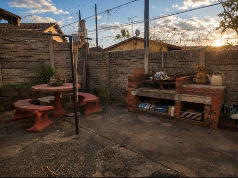 Outdoor patio area featuring a built-in brick braai, concrete paving, and perimeter walling with security razor wire.