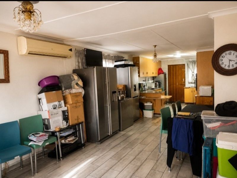 Open-plan living and kitchen area featuring tiled flooring, split-system air conditioning, and functional cabinetry, offering a versatile space for renovation and modernization.