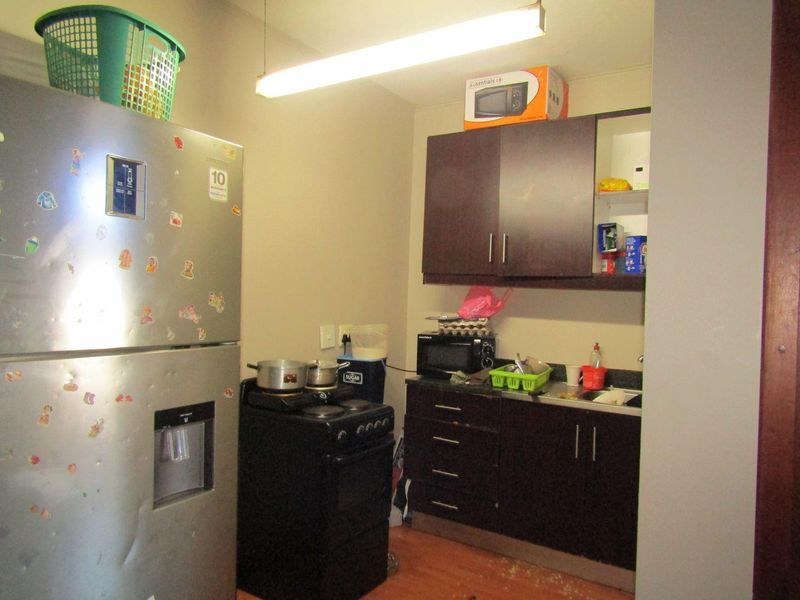Compact kitchen area featuring dark wood cabinetry, laminate countertops, and a stainless steel sink, requiring cosmetic updates to improve functionality and aesthetic appeal.