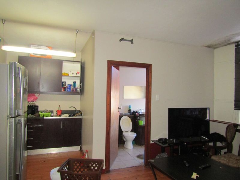 Open plan living area featuring a compact kitchen with dark cabinetry and direct access to an adjoining bathroom.