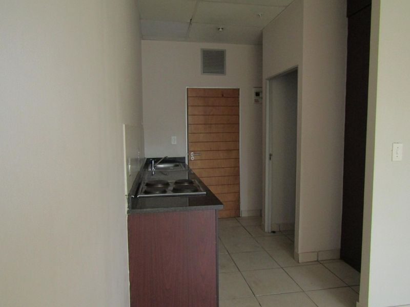 A compact kitchen area featuring built-in cabinetry, a granite countertop with an integrated hob and sink, and tiled flooring.