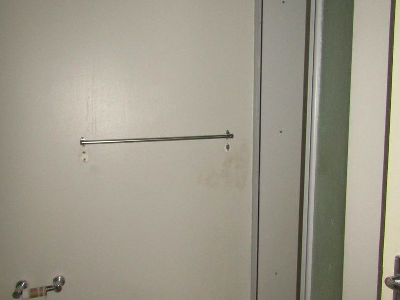 A basic bathroom featuring a shower enclosure and tiled flooring, currently showing signs of wear and wall staining requiring maintenance.