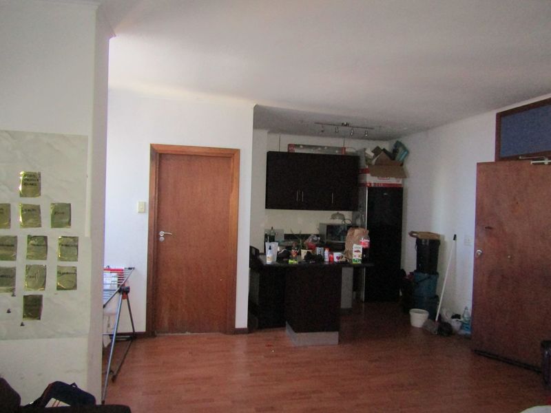 Open plan living area featuring laminate flooring and a compact kitchen corner with dark cabinetry.