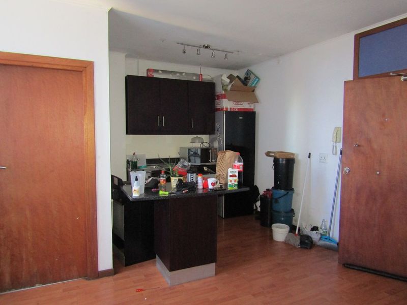 Compact kitchen area featuring dark cabinetry, granite countertops, and laminate flooring, requiring minor cosmetic updates to enhance its overall appeal.
