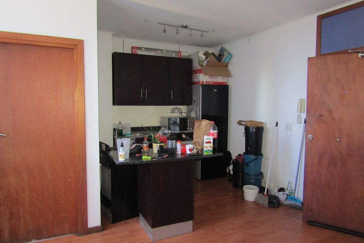Compact kitchen area featuring dark cabinetry, granite countertops, and laminate flooring, requiring minor cosmetic updates to enhance its overall appeal.