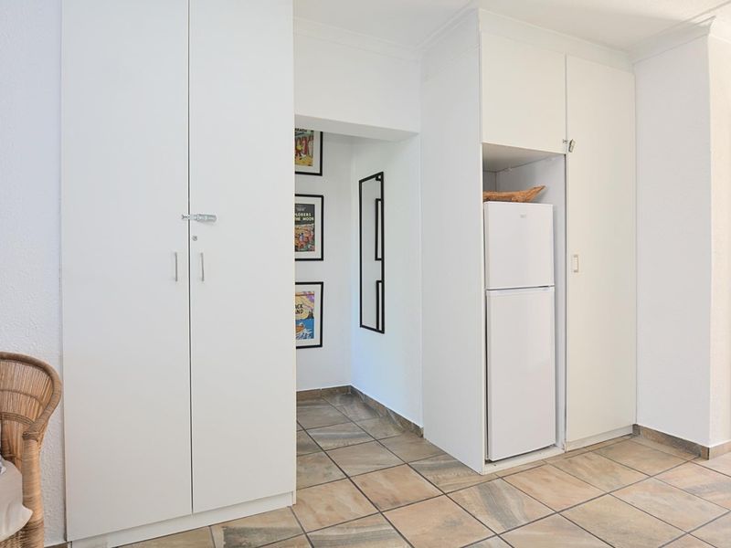 A bright hallway featuring neutral tiled flooring and ample built-in cupboard storage, providing a clean and functional transition space within the apartment.