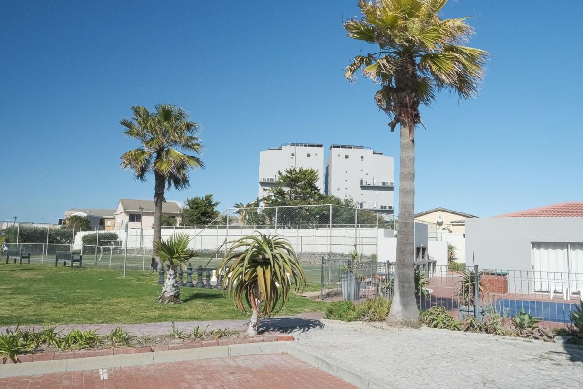Communal outdoor area featuring a tennis court, swimming pool, and landscaped garden space within the apartment complex grounds.