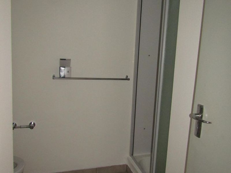 A functional bathroom featuring a shower enclosure and tiled flooring, presented in a clean, neutral, and empty state.