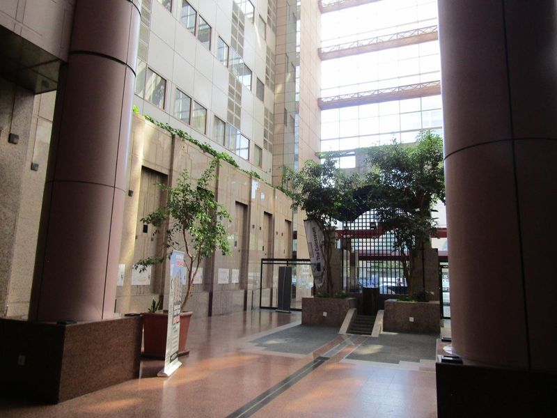 Spacious modern apartment building lobby featuring high ceilings, glass atrium, and polished granite flooring.