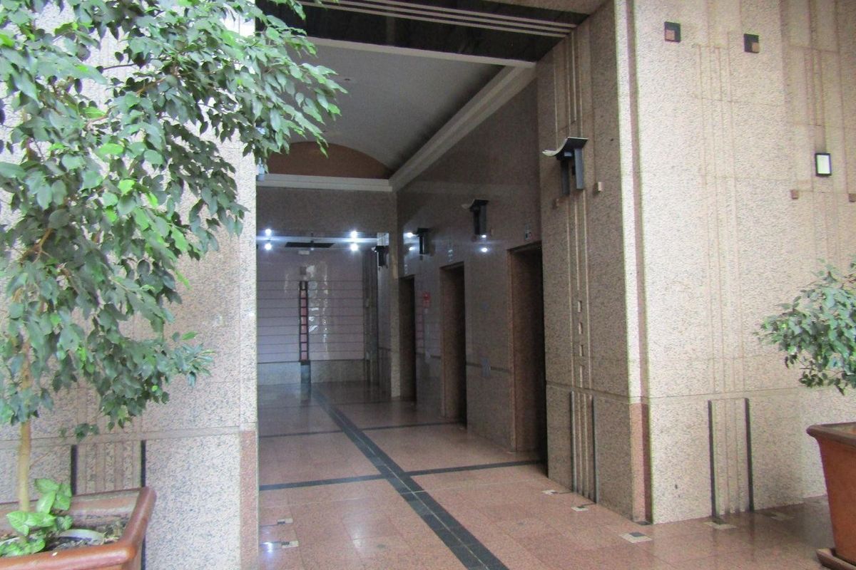 A formal apartment building entrance lobby featuring polished granite wall and floor finishes with a dedicated elevator bank.