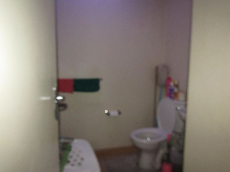A small bathroom featuring a standard toilet, towel rail, and toilet roll holder. The space requires updating and better lighting.