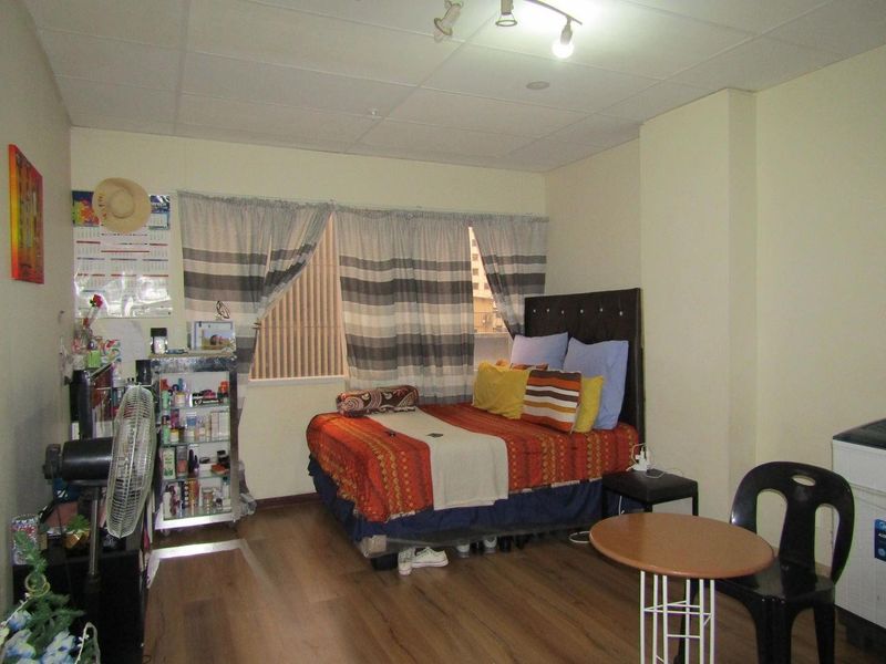 A bedroom featuring laminate flooring and a drop ceiling, offering a functional space with potential for cosmetic updates.