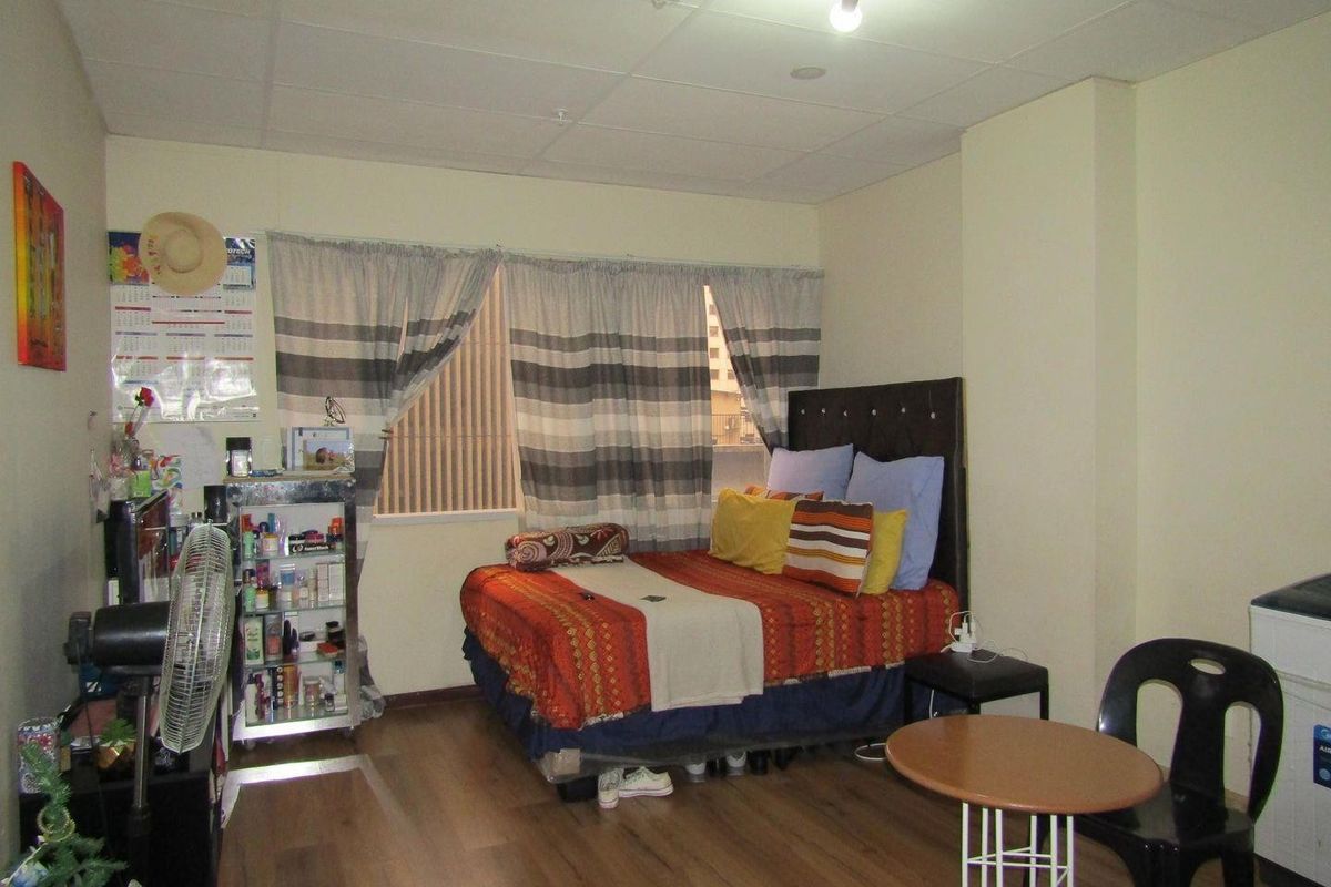 A bedroom featuring laminate flooring and a drop ceiling, offering a functional space with potential for cosmetic updates.