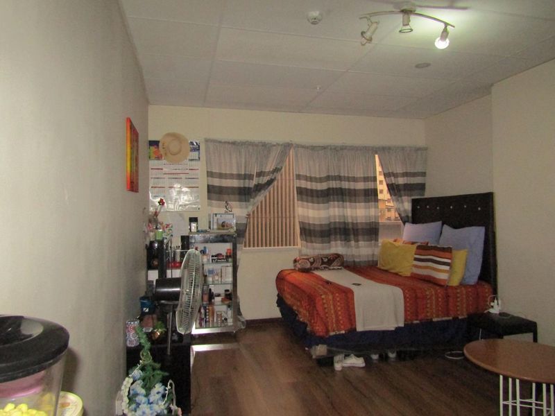 A bedroom featuring laminate flooring and a ceiling-mounted spotlight fixture. The room requires cosmetic updates to improve its overall condition and appeal.