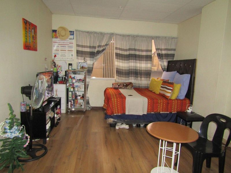 A bedroom featuring laminate flooring and a drop ceiling, providing a functional living space.