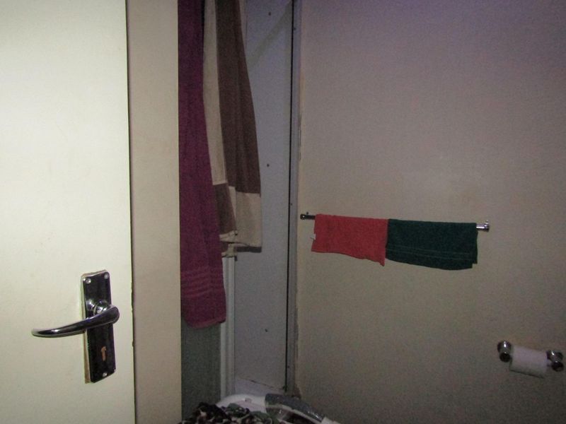 A compact bathroom featuring a shower enclosure, towel rails, and a toilet roll holder, requiring cosmetic updates to improve its overall condition.
