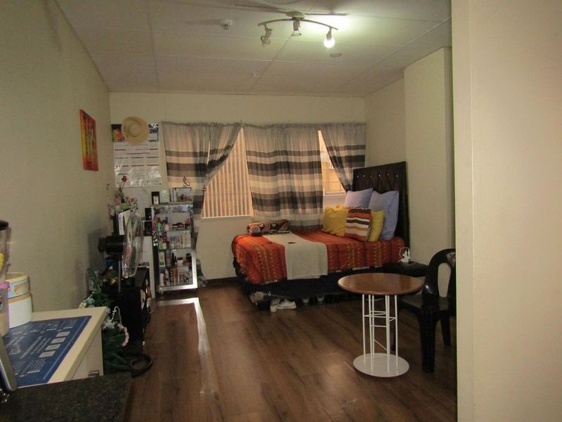 A functional bedroom featuring laminate flooring and ceiling-mounted track lighting, offering a practical living space within the apartment.