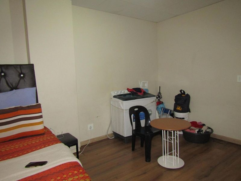 A bedroom featuring laminate flooring and neutral wall finishes, currently utilized as a multi-purpose living space.