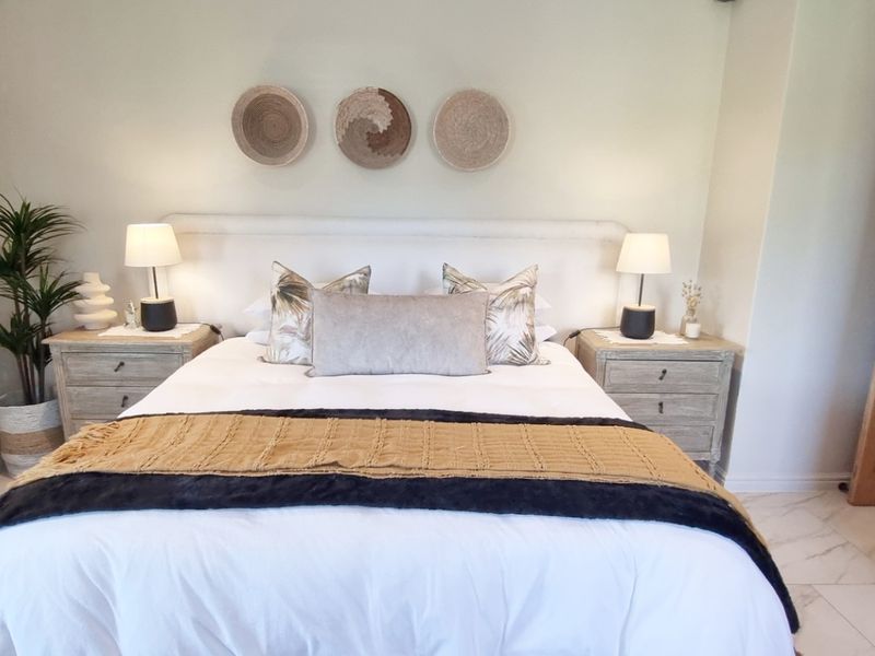 A well-maintained bedroom featuring neutral wall tones, tiled flooring, and a classic wooden door.
