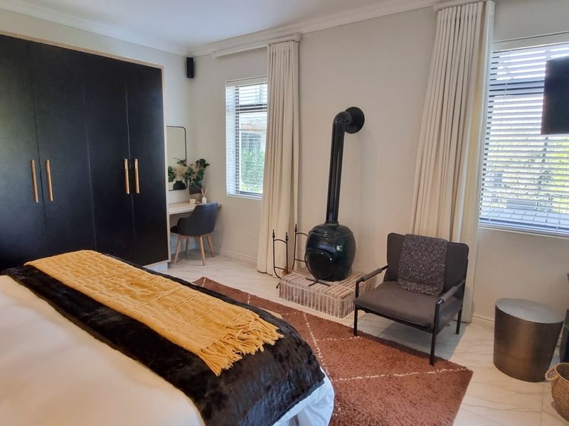 A well-maintained bedroom featuring a modern built-in wardrobe, tiled flooring, and a unique freestanding fireplace, creating a cozy and functional living space.