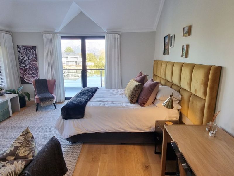 Spacious bedroom featuring vaulted ceilings, hardwood flooring, and sliding glass doors opening to a balcony with scenic views.