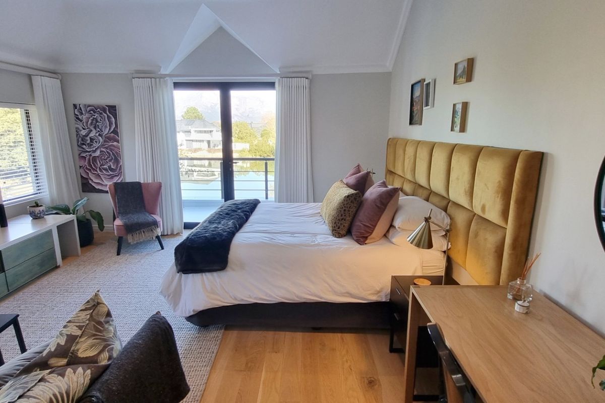 Spacious bedroom featuring vaulted ceilings, hardwood flooring, and sliding glass doors opening to a balcony with scenic views.