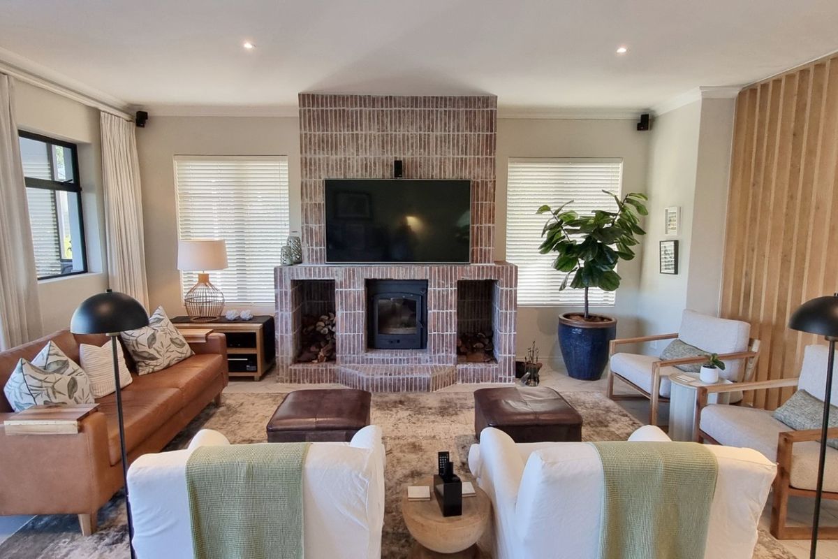 Spacious living room featuring a prominent brick fireplace with a built-in wood-burning stove, timber slat feature wall, and modern tiled flooring.