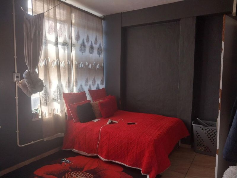 A bedroom featuring tiled flooring and dark painted walls with exposed electrical conduit, requiring cosmetic updates to improve the overall aesthetic.