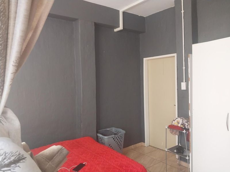 A bedroom featuring dark grey painted walls, tiled flooring, and visible surface-mounted electrical conduit.