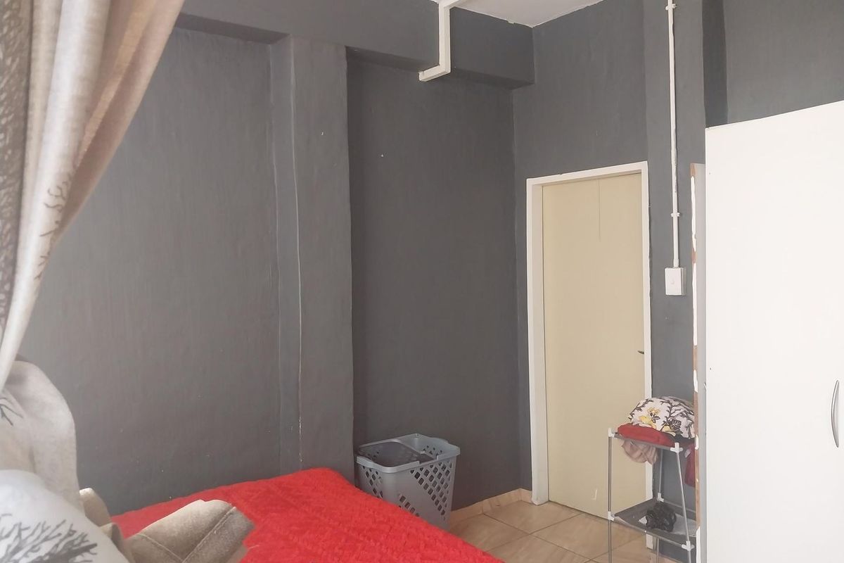 A bedroom featuring dark grey painted walls, tiled flooring, and visible surface-mounted electrical conduit.