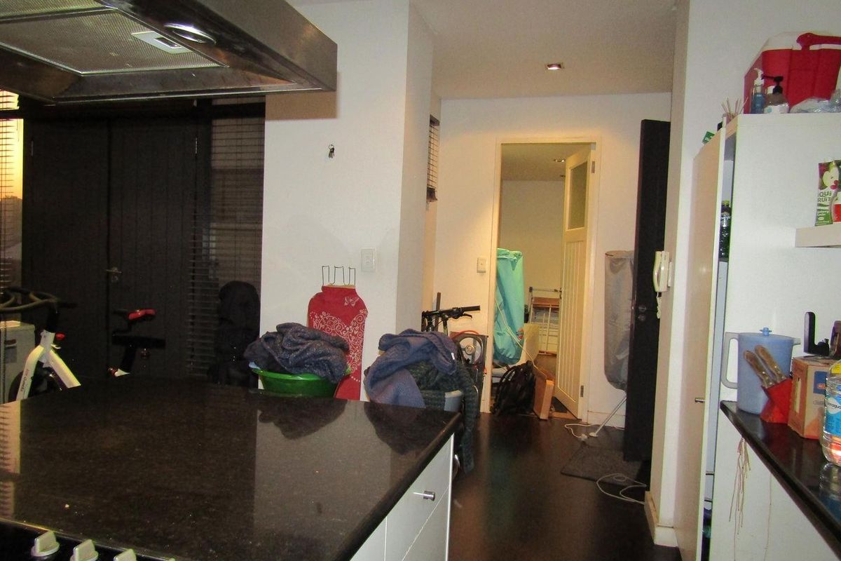 Kitchen area featuring dark granite countertops, a built-in hob, and an overhead extractor fan, leading to an adjacent room.