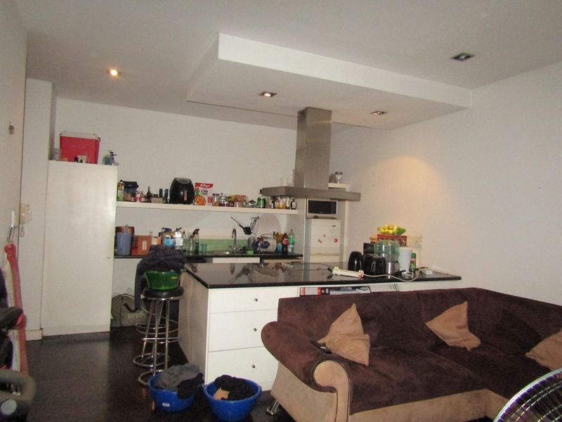 Open plan living area featuring a kitchen with a central island, granite countertops, and a stainless steel extractor fan.