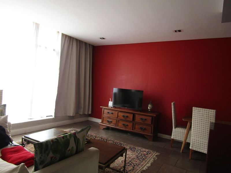 A living room featuring tiled flooring, recessed downlights, and a large window allowing for natural light.